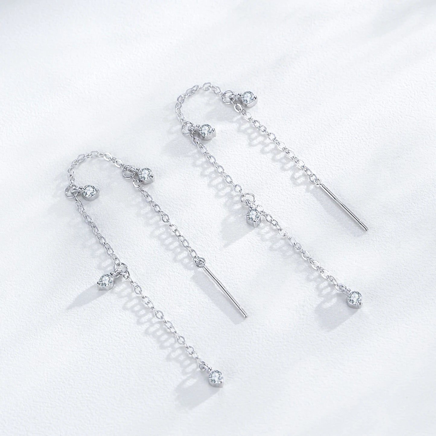Pair of silver earrings with dangling elements on a white background
